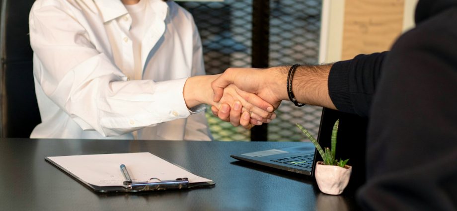 a man and a woman shaking hands in front of a laptop